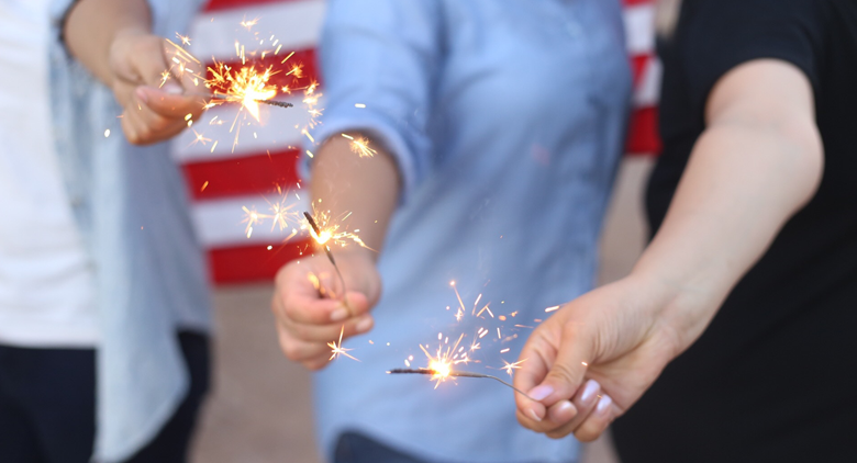 A group of kids playing with sparklers on the Fourth of July.