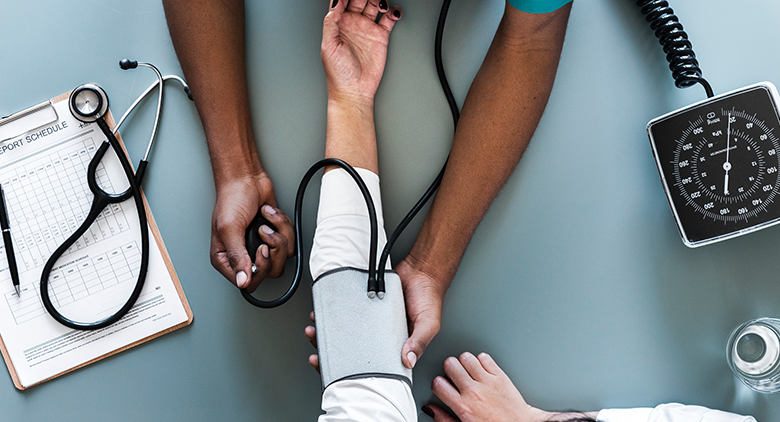 A black nurse taking a white patient's blood pressure. 