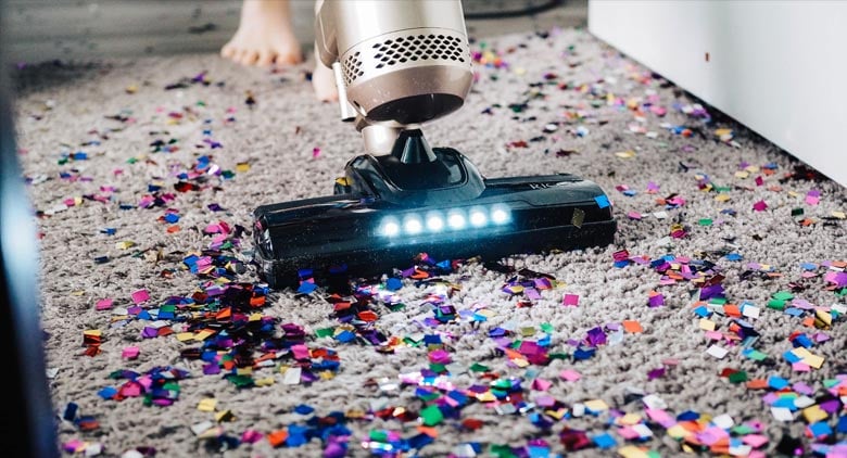 A gig economy worker vacuuming confetti from a floor.  