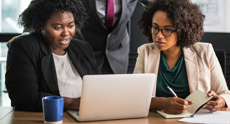 Two black female HR professionals using an HR platform for daily HR tasks. 
